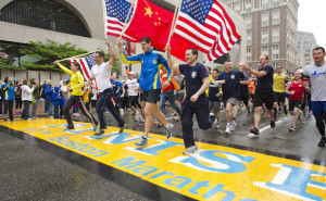Runners holding American flags and a Chinese flag cross the finish line after completing the final mile of the Boston Marathon course during "#onerun" in Boston, Massachusetts, May 25, 2013. The event was organized to give athletes and spectators an opportunity to complete the final mile of the Marathon that was cut short when two bombs exploded at the finish line.   REUTERS/Dominick Reuter  (UNITED STATES - Tags: SPORT ATHLETICS TPX IMAGES OF THE DAY)